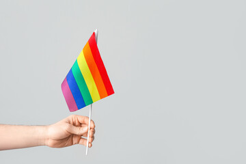 Male hand with LGBT flag on light background