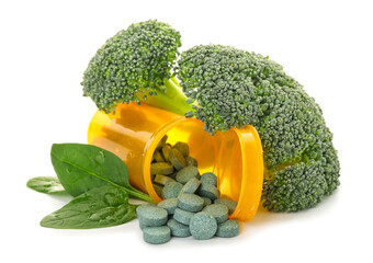 Fresh broccoli and bottle of pills on white background