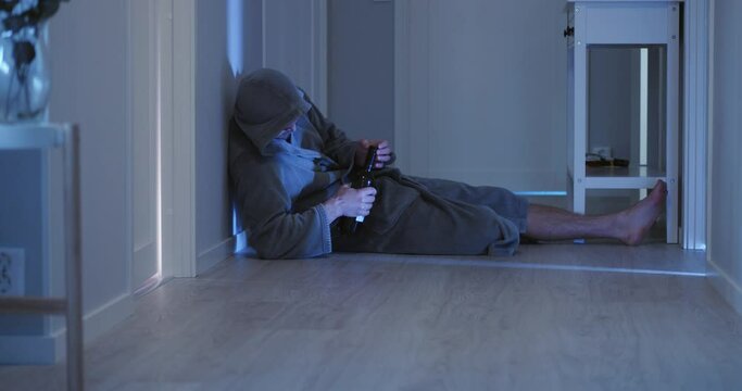 Drunk man dressed in hooded bathrobe lying on floor. Gimbal, low POV