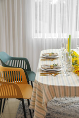 Dining table with beautiful setting and floral decor in light room