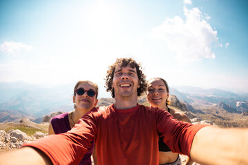 Photo of a group of friends taking a selfie. Smiling and happy people while traveling in the mountains.