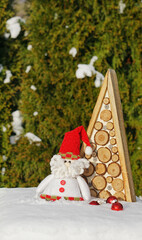 Toy Santa Claus with a Christmas tree on the snow. Winter holiday theme. Happy New Year. Space for text. Happy Holidays