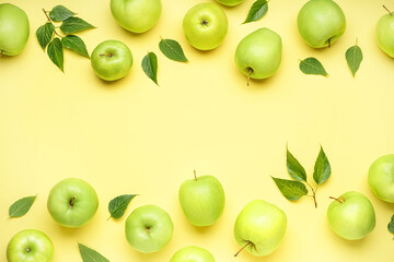 Composition with ripe green apples and leaves on yellow background