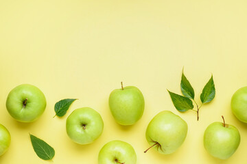 Composition with ripe green apples and leaves on yellow background