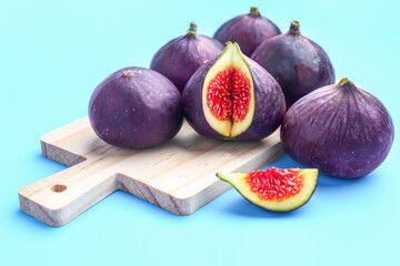 Wooden board with fresh ripe figs on color background, closeup