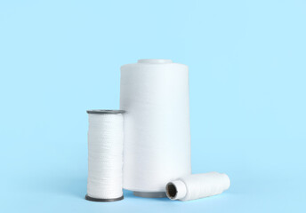 White thread spools on color background