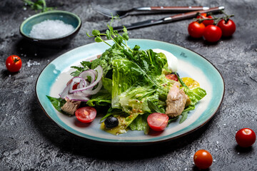 Tuna salad with poached, egg, lettuce, cherry, tomatoes olives and corn on dark stone or concrete background. Top view. copy space