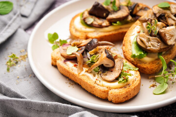 Plate of tasty toasts with cream cheese and mushrooms on grunge background, closeup
