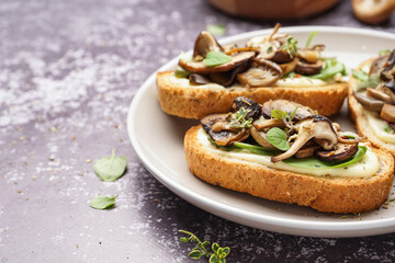 Plate of tasty toasts with cream cheese and mushrooms on grunge background, closeup