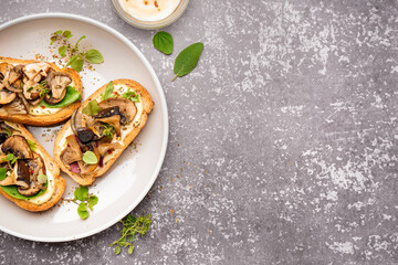Plate of tasty toasts mushrooms and bowl of sauce on grunge background