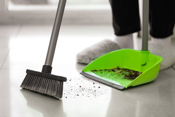 Woman sweeping tile floor with broom and dustpan, closeup - Powered by Adobe