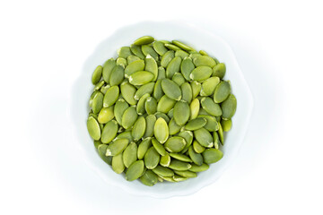 Peeled pumpkin seeds in a bowl on a white isolated background. View from above.