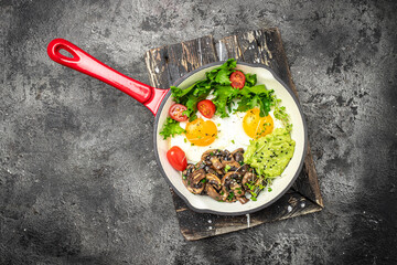 Breakfast skillet pan of fried egg, avocado and mushrooms. Ketogenic diet. Low carb high fat...
