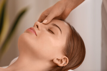 Fototapeta na wymiar Pretty young woman receiving face massage in beauty salon
