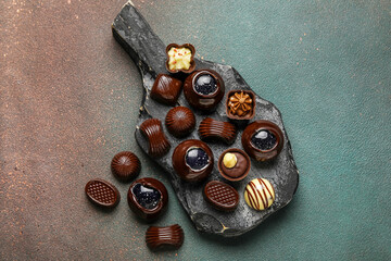 Cutting board with chocolate candies on grunge background