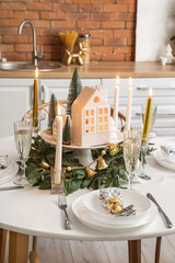Christmas table setting with candle holders and fir trees in kitchen, closeup