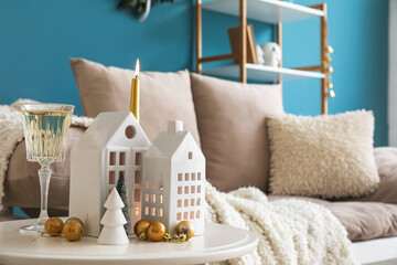 Candle holders, Christmas trees, balls and glass of champagne on table in living room, closeup