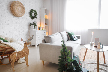 Interior of living room with sofa, Christmas tree and candle holders