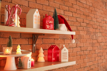 Shelves with candle holders, Christmas trees and Santa hat on brick wall