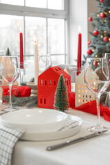 Christmas table setting with candle holders and fir branches in dining room, closeup