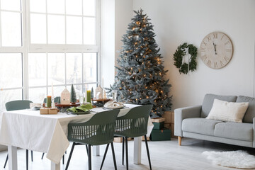 Dining table with setting, Christmas tree and sofa in interior of room