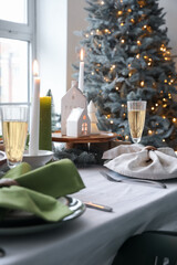 Christmas table setting with candle holders and fir branches in dining room, closeup