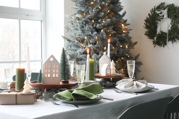 Christmas table setting with candle holders, presents and fir trees in dining room