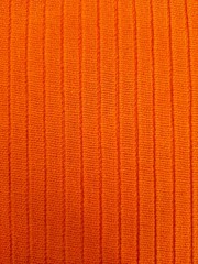 Orange textured knitwear background. Close-up of the fabric with vertical lines. Textile design.