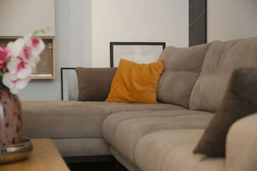 Grey comfortable sofa with mustard yellow cushion and coffee table with flower vase in the living room, modern living concept.