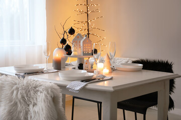 Table setting with burning candles and Christmas balls in dining room
