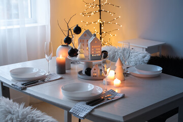 Table setting with burning candles and Christmas balls in dining room