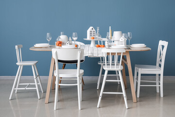 Christmas table setting with candle holders and mandarins near blue wall