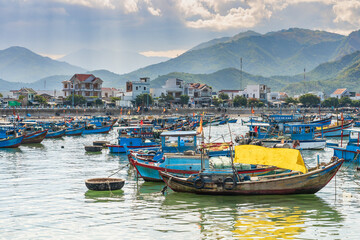 Fototapeta na wymiar Colourful fishing boats in a small harbour in front of a mountain range at Vihn Luong Fishing Village in Vietnam