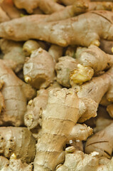 Close-up view of knobbly ginger roots piled together for sale at a market