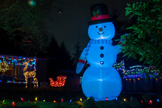 Luminous inflatable figure of Snowman decorating front yard at night