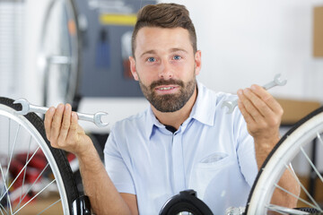 man fixing bike wheel in store