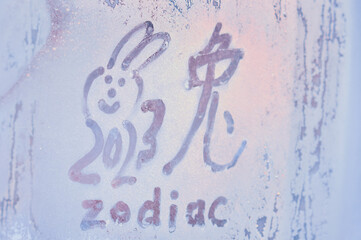 New Year's drawing on a frozen window. The hieroglyph of the rabbit is the zodiac symbol of the...