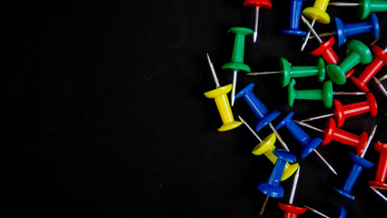 multicolored thumbtacks on a black background