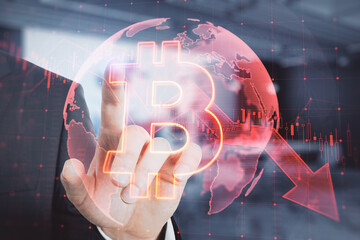 Close up of businessman hand pointing at falling global red bitcoin hologram on blurry background. Cryptocurrency, market fall and stock exchange concept. Double exposure.