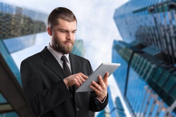 Rich business man standing outdoors and using digital table
