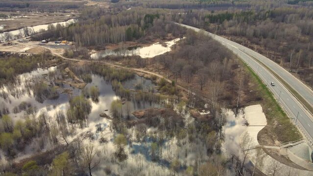 Large-scale flooding of the river, spring flood and flooded fields, aerial view. Snow is melting, high water levels, flooded banks, fields, trees. Warm sunny day, soft light. UHD 4K.