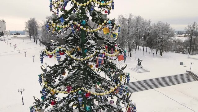 Golden and sparkling garlands on the Christmas tree, city square, aerial view. New Year's, green spruce fabulously decorated and covered with snow. City of Vladimir, Cathedral Square, Russia. UHD 4K.