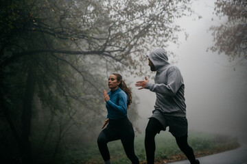 Woman and man in sports outfits in a full sprint on the forest road racing with each other. 
