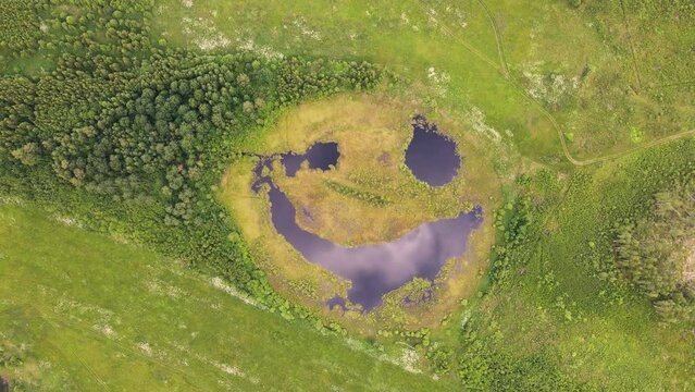 Aerial view of a fantastic lake that seems to be laughing cunningly. A pond with big eyes. The beauty of nature. A joyful expression on a natural lake. Happy nature smiles. 4K UHD.