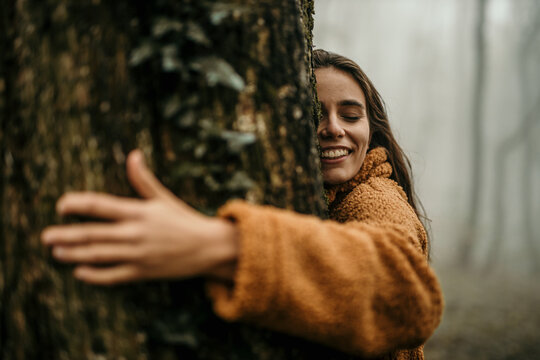 Cheerful woman hugging a tree in the forest, collecting natural energy from it. Ecology and nature, Protect the environment and save the forest, Energy sources for renewable, Earth day.