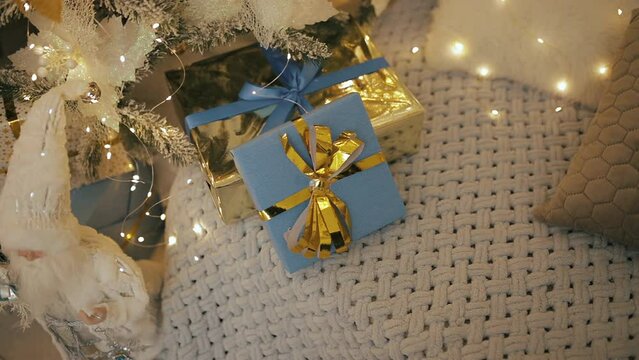 Packed Christmas presents, blue gifts boxes with golden yellow bows ribbons. New Year 2023 in Ukraine. National flag colors. Decorated tree, garland lights bokeh