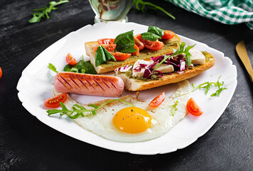 Breakfast. Fried egg, sausage and sandwiches with pesto, cheese, tomatoes with green.