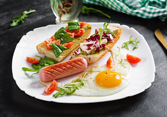 Breakfast. Fried egg, sausage and sandwiches with pesto, cheese, tomatoes with green.