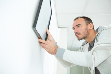 Fototapeta premium man hanging picture frames on wall at home