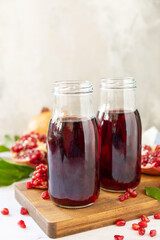 Pomegranate juice in glass bottles and fresh pomegranate fruits. Healthy drink diet immunity vitamins or vegetarian food concept. Copy space.